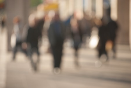 People walking down the street in the evening beautiful light at sunset the photo is purposely made out of focus no faces are recognisible Stock Photo