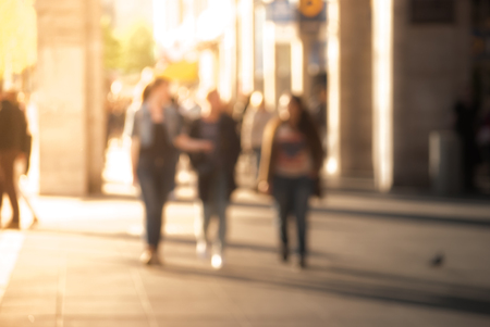 People walking down the street in the evening beautiful light at sunset the photo is purposely made out of focus no faces are recognisible