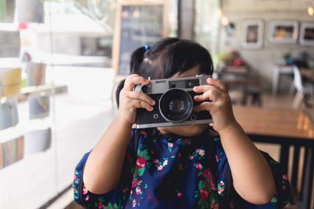 Girl in holding a vintage photo camera in hands at coffee cafã©