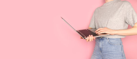 Banner with woman hold in hands laptop remote work concept in front of pink background selective focus