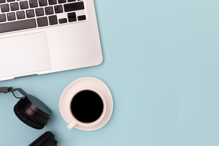 Headphones cup of black coffee and laptop on a blue background online work concept with place for text