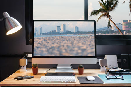 Graphic designer s workspace on the beach with a pen tablet a computer and sand backgroud for text