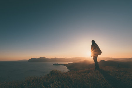 Young standing man with backpack hiker on the stone on the seashore at colorful sunset sky beautiful landscape with sporty man rocks sea and clouds at sunset sporty lifestyle Stock Photo