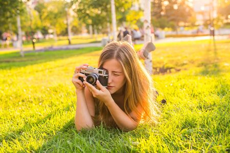 Woman the photographer with old camera lays on a grass