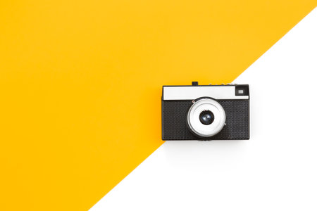 Old film camera on a yellow and white background flat lay