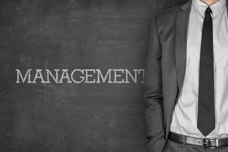 Management on blackboard with businessman in a suit on side