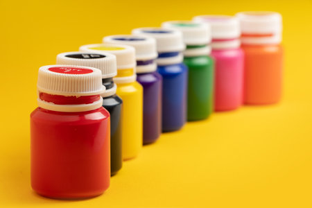 Bottles with multicolored paints on yellow background