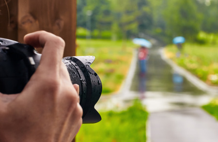 Photographer shooting hands close up park in the rain with umbrellas and people