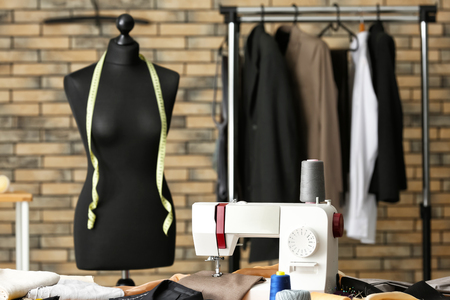 Tailor s workplace with sewing machine and mannequin in atelier