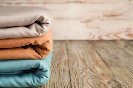 Stack of clean bed sheets on table closeup