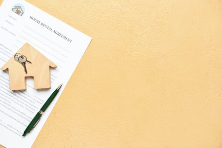 Contrato de alquiler de casa con bolígrafo, llave y juguete de madera sobre fondo beige