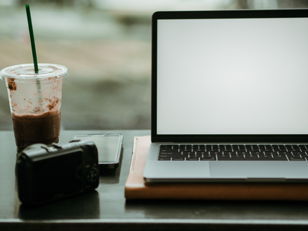 Empty screen laptop with camera and ice coffee in the cafe concept of freelance work