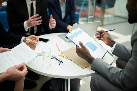 Mid section crop of unrecognizable business people meeting in office focus on african man holding clipboard copy space