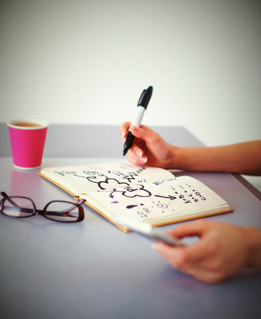 Young woman writes to diary on a white table