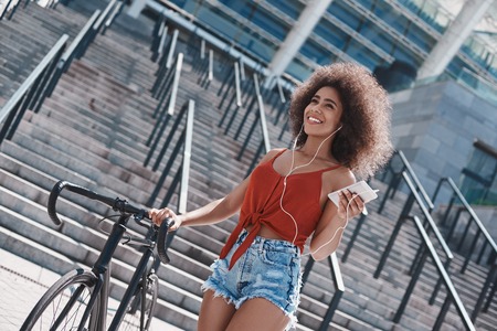 Mujer joven en estilo libre de auriculares en la calle caminando cerca de s