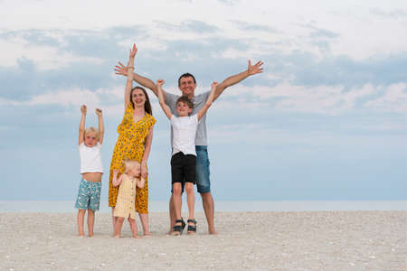 Retrato de familia feliz en el fondo de la playa del mar. Padres y tres hijos. Estilo de vida familiar.