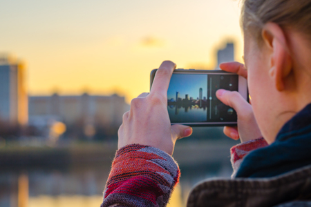 Jonge vrouw maakt foto's van het panorama van de stad op een smartphone.