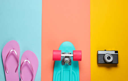 Hipster outfit skateboard with retro camera flip flop on colored background creative fashion minimalism trendy old fashionable style minimal summer fun music concept top view Stock Photo