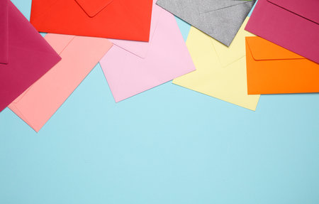 Many colored envelopes on a blue background with copy space