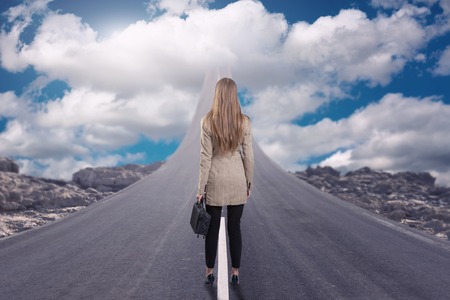 A businesswoman standing on road that goes up to the sky Stock Photo