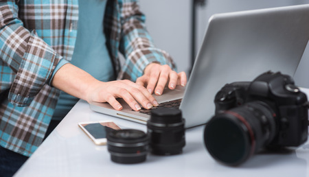 Female photographer working in her studio hands close up and digital camera on foreground