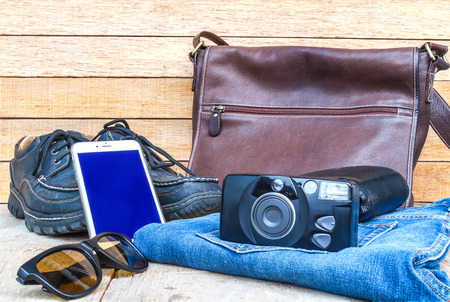 Travel casual outfits with camera smartphone shoes wallet leather bag sunglasses and jean on wooden table travel concept Stock Photo