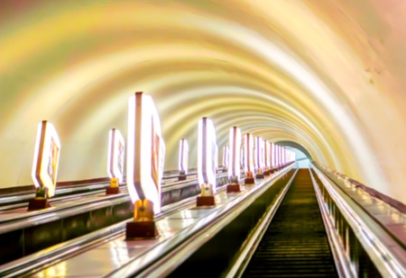 Bright lamps on one side and white wall on another dark stairs in metro of big city in light and shadows