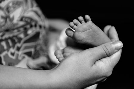 Tiny newborn baby s feet being held by father s hand