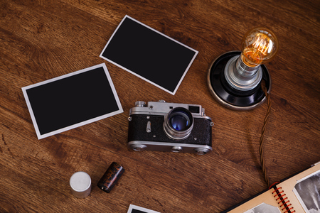 Vintage photo camera blank photo frames retro lamp light bulb old album and camera rolls wooden rustic background Stock Photo