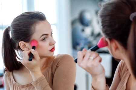 Woman holds cosmetic brush in the face