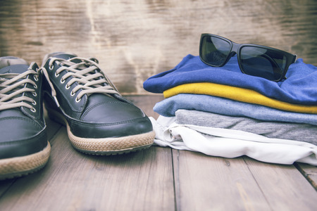 Man sneakers and clothing on wooden table