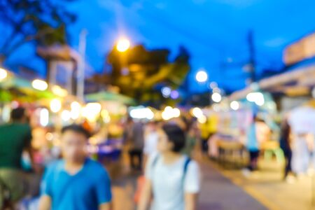 Group of blurred people shopping in outdoor market with light bokeh Stock Photo