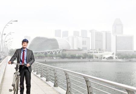 Smiling caucasian businessman with his bike Stock Photo