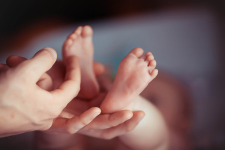 Newborn baby feet in mother