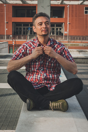 Man in short sleeve shirt sitting outdoor with crossed legs