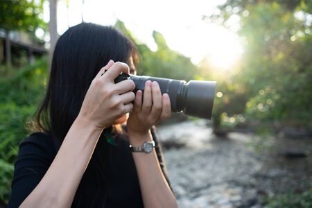 Asian woman photographer in nature taking pictures right side