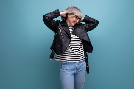 Cheerful 60s mature woman in a stylish jacket on a bright background Stock Photo