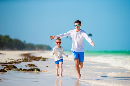 Feliz padre y su adorable hija pequeña en la playa de arena blanca