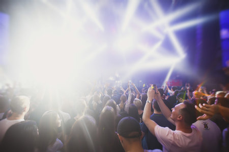 A crowded concert hall with stage stage lights rock show performance with people silhouettes during live music show performance with crowd of audience