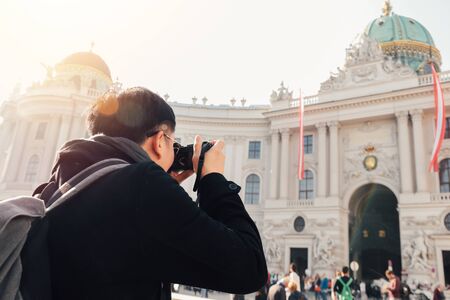 Giovane turista asiatico che scatta foto con la fotocamera in mano vicino al palazzo Hofburg a Vienna, Austria, Europa. Famoso luogo turistico popolare in Europa