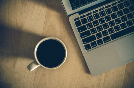 Top view of laptop notepad and coffee cup on office wooden background flat lay