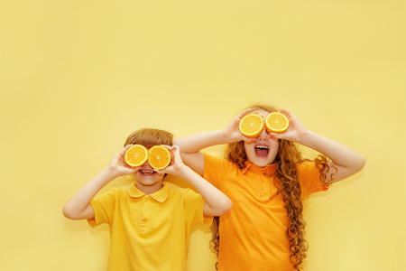 Śmiejące się dzieci z pomarańczowymi oczami pokazują białe zdrowe zęby na żółtym tle. koncepcja zdrowego, stylu życia i szczęśliwego dzieciństwa. Zdjęcie Seryjne