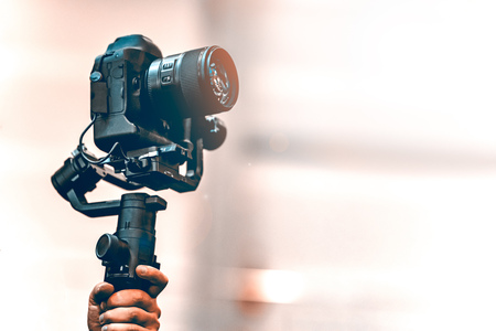 Video shooting with a camera with a tripod with a black stabilizer the background is blurred