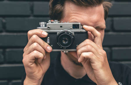 A young man takes a photo with a vintage film camera