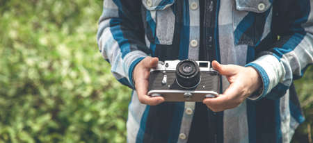 Vintage film camera in male hands on a hike in nature