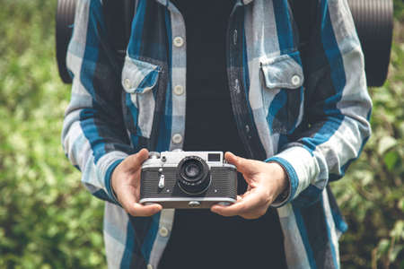 Vintage film camera in male hands on a hike in nature