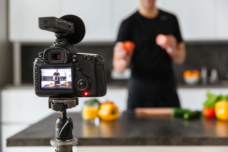 Close up of a video camera filming young man blogger at the kitchen