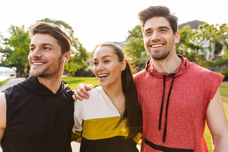 Foto de gente feliz y alegre usando ropa deportiva sonriendo y abrazándose mientras hace ejercicio en el parque de la ciudad