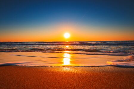 Amanecer o atardecer en la playa con cielo azul claro y sol naciente Foto de archivo