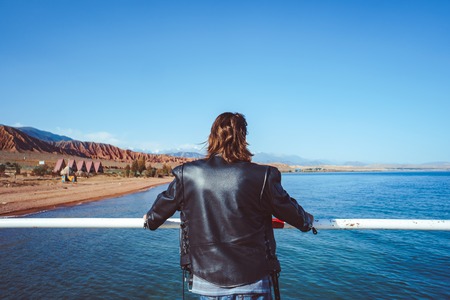 A middle aged man in sports clothes standing on the pier and watching sunset